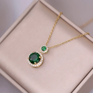 Elegant gold necklace with emerald green gemstone pendant and pave diamonds in a jewelry box