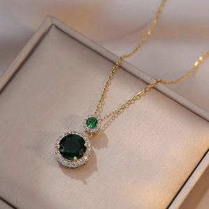 Elegant emerald green zircon pendant necklace with gold chain on velvet display