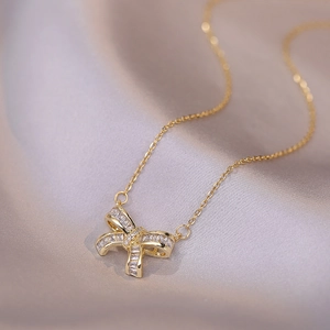 Collier nœud doré élégant avec zircons cubiques sur un fond en tissu de soie