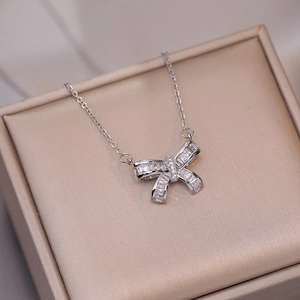 Collier à pendentif nœud en zircon avec pierres baguette dans une boîte en soie