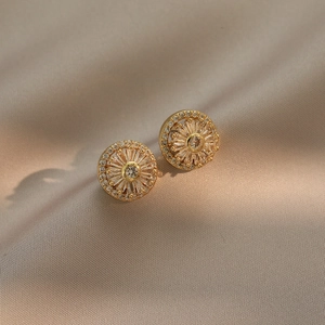 Elegant gold sunburst stud earrings with sparkling zircons on champagne silk fabric