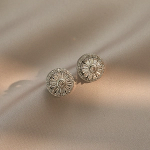 Detail of round starburst stud earrings with brilliant zircon stones on champagne fabric