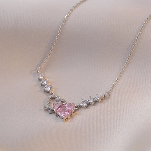 Collar de acero inoxidable con colgante de corazón de circón rosa sobre seda beige