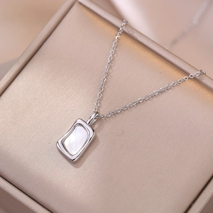 Collier à pendentif carré en nacre sur un coffret à bijoux en satin champagne
