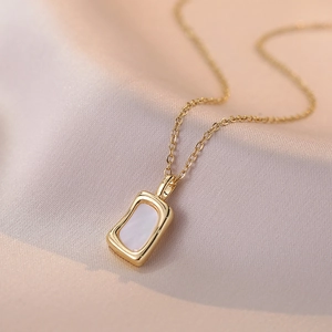 Collier doré avec pendentif en nacre sur fond en soie rose doux élégant