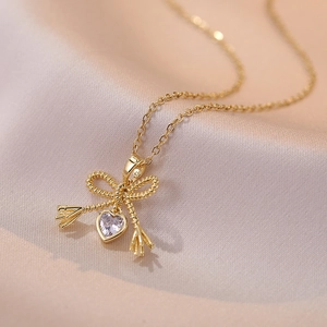Gold bow necklace with twisted rope texture and heart-shaped zircon pendant on silk
