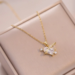 Elegant gold heart planet necklace with a large clear crystal pendant on a jewelry box
