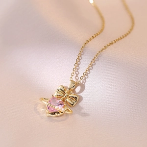 Collier doré élégant avec cœur rose, nœud papillon et accents de bague planétaire
