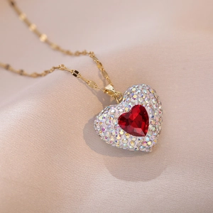 Golden heart necklace with red crystal and sparkling pavé stones on champagne silk