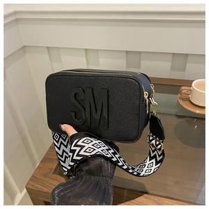 Détail du sac carré Saffiano noir avec logo SM et bandoulière large géométrique
