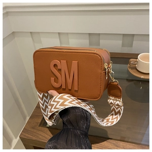 Vue détaillée du sac bandoulière marron avec logo embossé et sangle large