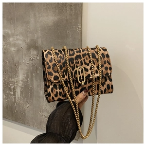 Detail of leopard print flap bag with elegant gold chain strap and oval metal clasp