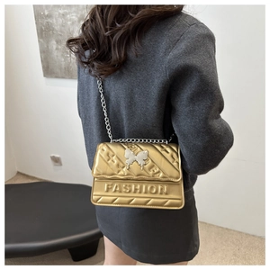 Detailed view of quilted gold chain bag with silver butterfly buckle and fashion relief