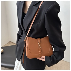 Close-up of brown matte leather shoulder bag with golden ring buckle and fine stitching