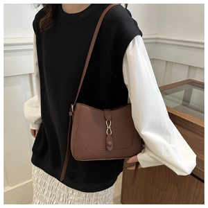 Detail view of dark brown semi-circular crossbody bag with golden decorative buckle