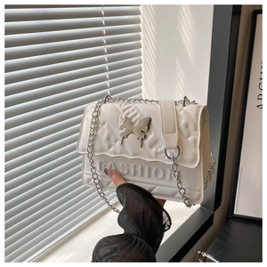 Close-up of white quilted handbag featuring a silver butterfly clasp and metal chain strap
