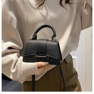 Detailed macro view of black litchi grain leather handbag with gold-tone metal hardware