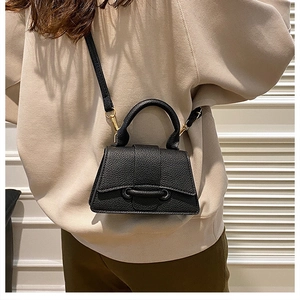 Detail of black lychee grain leather mini bag with gold hardware and top handle