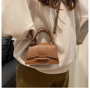 Detail of caramel litchi grain leather mini bag with golden metal buckle and top handle