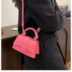Mini hot pink leather crossbody bag with top handle and pebble texture for modern styling