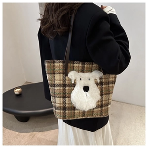Dettaglio della borsa tote scozzese con patch cane indossata sulla spalla