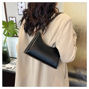 Detail of minimalist black underarm bag showing matte leather texture and sleek metal buckle
