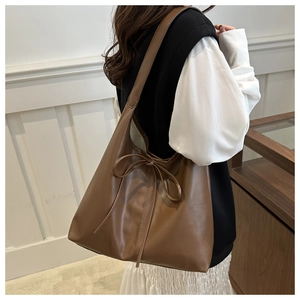 Detail of dark brown leather hobo bag with decorative bow on a fashion model