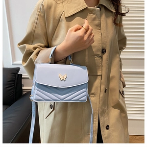 Detail of light blue chevron quilted crossbody bag with butterfly metal buckle