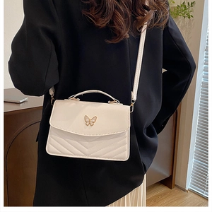 White mini crossbody bag with V-quilted faux leather and gold butterfly clasp on model