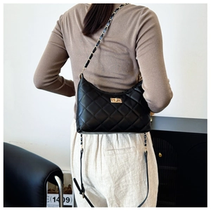 Detail of black quilted shoulder bag featuring gold chain strap and metallic twist lock