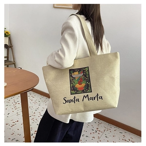 Detail of canvas tote bag with Santa Marta print worn by model from a side-back view