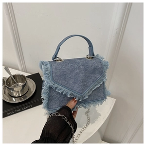 Detail of vintage blue denim crossbody bag with frayed fringe edges and chain strap
