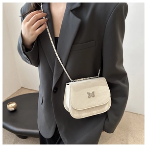 Détail du sac selle crème avec boucle papillon argentée et bandoulière en chaîne