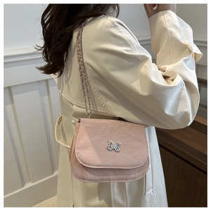 Détail du sac selle rose clair texturé avec fermoir papillon et bandoulière chaîne
