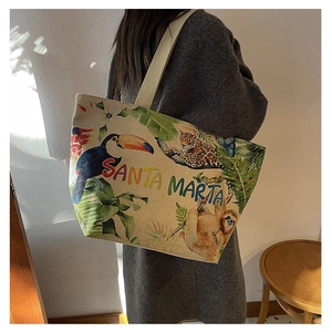 Detail of a large canvas tote bag with tropical embroidery worn over the shoulder