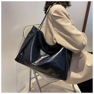 Vue détaillée du grand sac cabas noir brillant montrant sa texture souple et ses anses