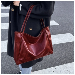Photo street style d'un cabas en cuir vernis bordeaux montrant texture et fines lanières