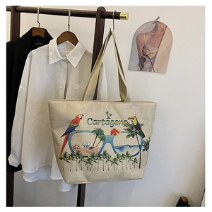 Detail of canvas tote bag featuring vibrant tropical parrot and palm leaf embroidery