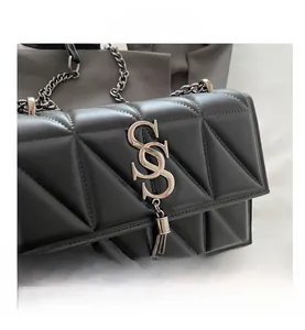 Detailed view of black triangular quilted leather bag with silver tassel and logo
