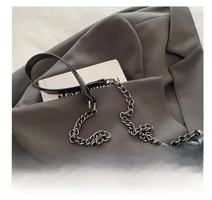 Detail of black quilted shoulder bag with S-shaped metal logo and chain strap