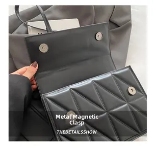 Detail view of the secure dual magnetic buckles on the quilted black leather shoulder bag