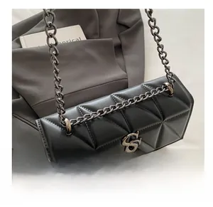 Detail view of black quilted crossbody bag showing triangular pattern and metal chain