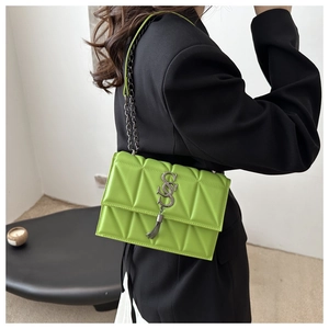 Quilted green shoulder bag with metal S-shaped logo and chain strap on female model