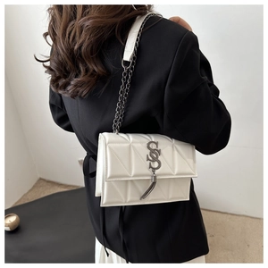 Detail of white quilted crossbody bag with metal tassel logo on black blazer outfit