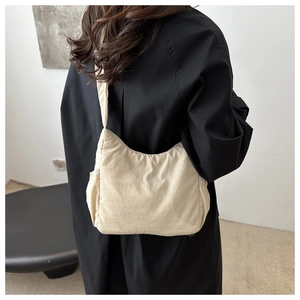 Détail du sac demi-lune en nylon beige avec plis et poche latérale fonctionnelle