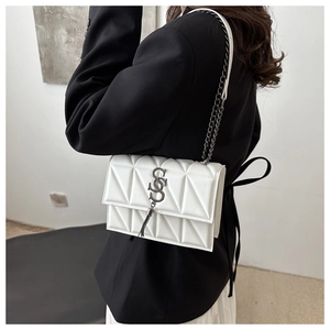 Detail of white quilted crossbody bag with silver S-logo and chain tassel on black blazer