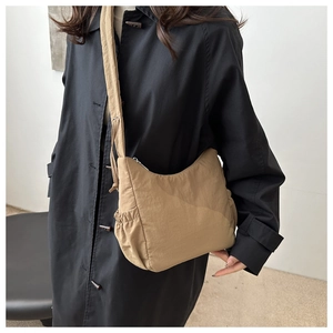Detail of khaki nylon crescent crossbody bag with pleated texture on model for daily commute