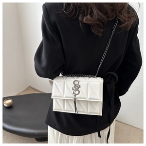 Rear view of model wearing a white quilted crossbody bag with metal S-logo and chain strap