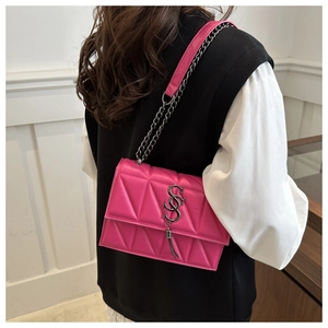 Detail of pink quilted leather handbag with silver logo, tassel and chain strap