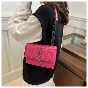Detail of fuchsia quilted crossbody bag featuring silver S-logo and fringe tassel charm